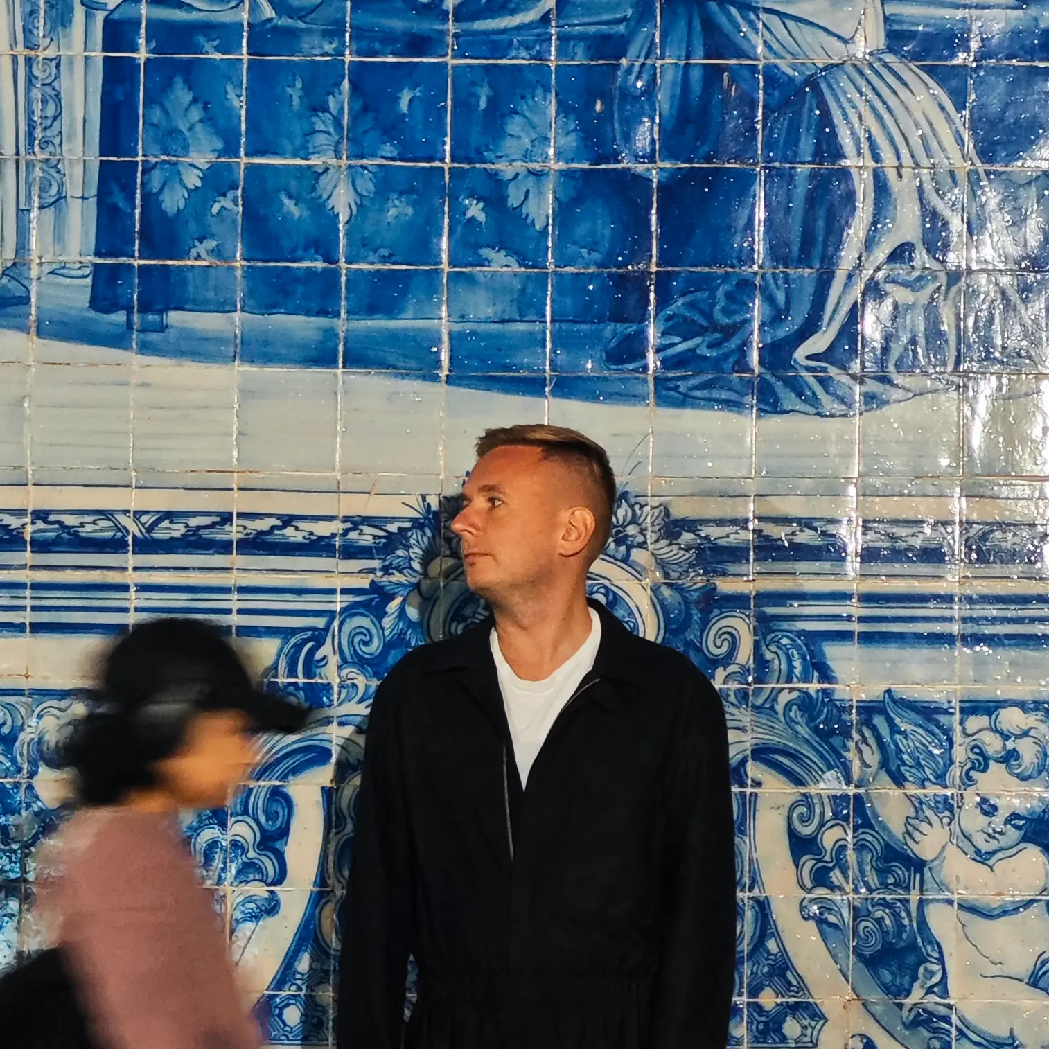 A traveller standing in front of a large blue azulejo mural in Porto